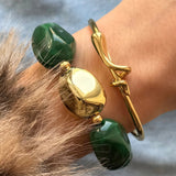 Bracelet fantaisie à grosses perles vertes imitation malachite et pépite dorée, porté au poignet avec un jonc fin doré à nœud marin.