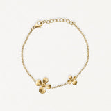 Bracelet en acier inoxydable couleur or avec deux charmes fleurs délicates, chaîne fine et fermoir mousqueton.