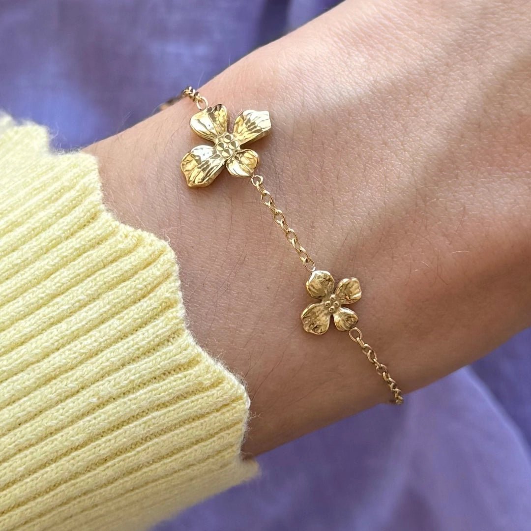 Bracelet en acier inoxydable doré, chaîne fine, avec deux pendentifs fleurs martelées au poignet.