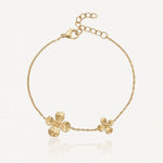 Bracelet chaîne doré avec deux fleurs texturées, une grande et une plus petite, et un fermoir mousqueton ajustable.
