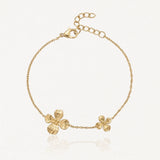 Bracelet chaîne doré avec deux fleurs texturées, une grande et une plus petite, et un fermoir mousqueton ajustable.