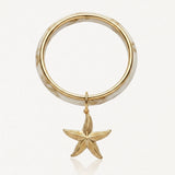 Bracelet jonc marbré crème et or avec un pendentif étoile de mer dorée texturée.