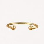 Bracelet jonc rigide ouvert en métal doré avec extrémités arrondies en forme de goutte, vue de face sur fond blanc.