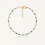 Bracelet en acier inoxydable doré, perles blanches et apatite facettée bleue. Fermoir mousqueton et chaînette d'extension.