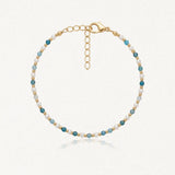 Bracelet en acier inoxydable doré, perles blanches et apatite facettée bleue. Fermoir mousqueton et chaînette d'extension.