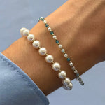 Deux bracelets en acier inoxydable doré au poignet. L'un a de grandes perles blanches, l'autre des perles et de l'Apatite