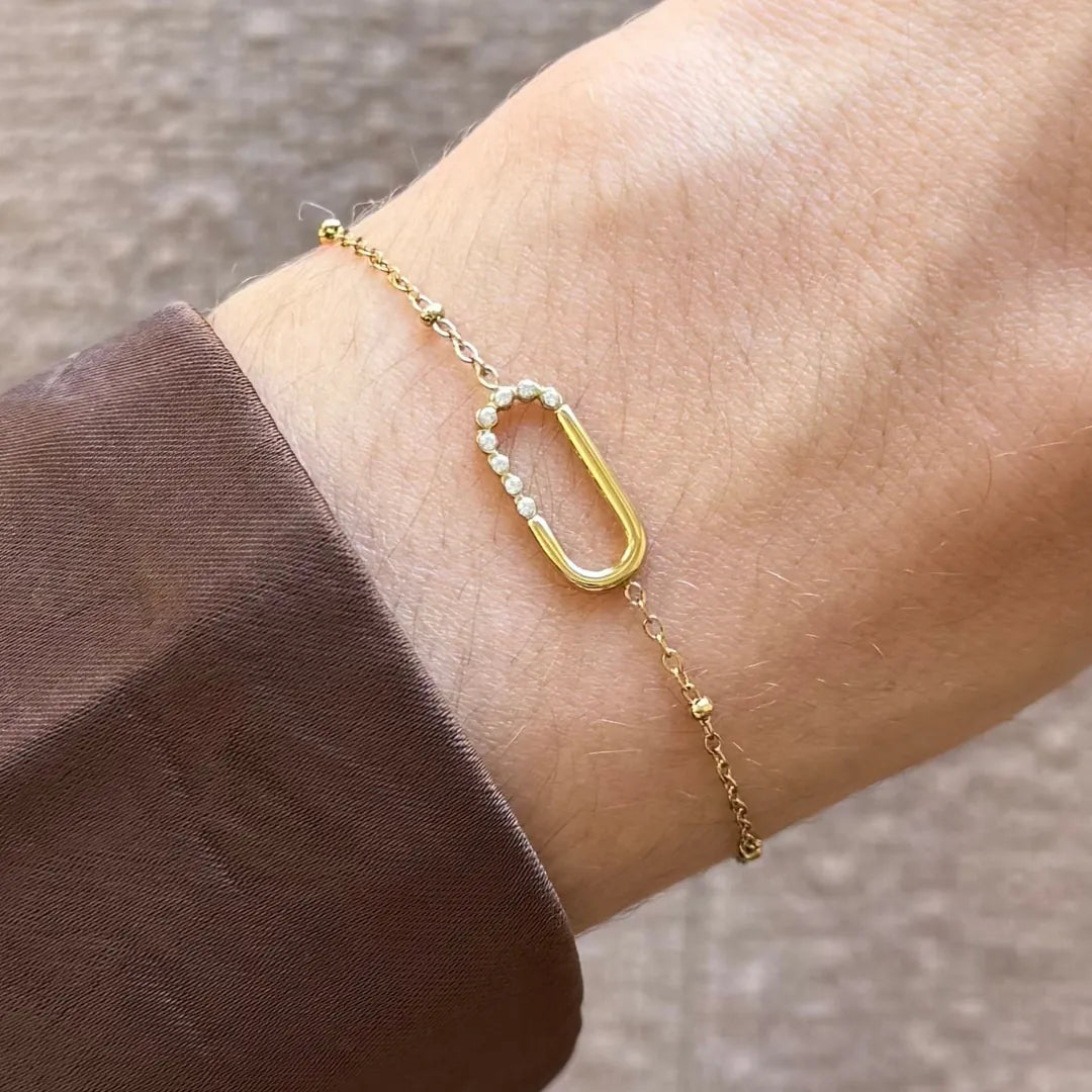 Bracelet Kylie en acier inoxydable doré avec un motif en U orné de strass en zirconium porté au poignet