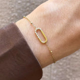Bracelet Kylie en acier inoxydable doré avec un motif en U orné de strass en zirconium porté au poignet