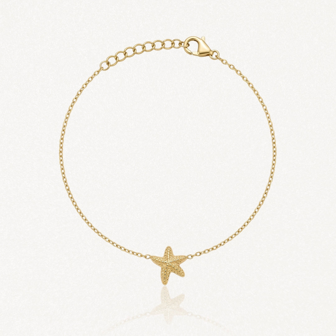Bracelet doré fin avec une étoile de mer texturée au centre, fermoir mousqueton et chaîne d'extension.