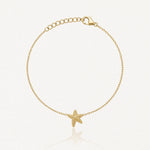 Bracelet doré fin avec une étoile de mer texturée au centre, fermoir mousqueton et chaîne d'extension.