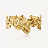 Bracelet doré de style manchette, orné de multiples fleurs en relief aux centres texturés.