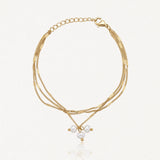 Bracelet doré à trois chaînes fines à maillons plats, fermoir mousqueton, chaînette d'extension et trois perles baroques