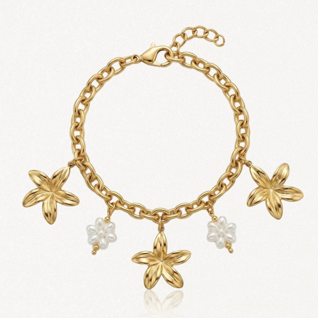 Bracelet chaîne dorée à maillons épais avec 3 breloques fleurs dorées et 2 breloques fleurs en perles blanches.
