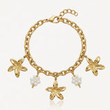Bracelet chaîne dorée à maillons épais avec 3 breloques fleurs dorées et 2 breloques fleurs en perles blanches.