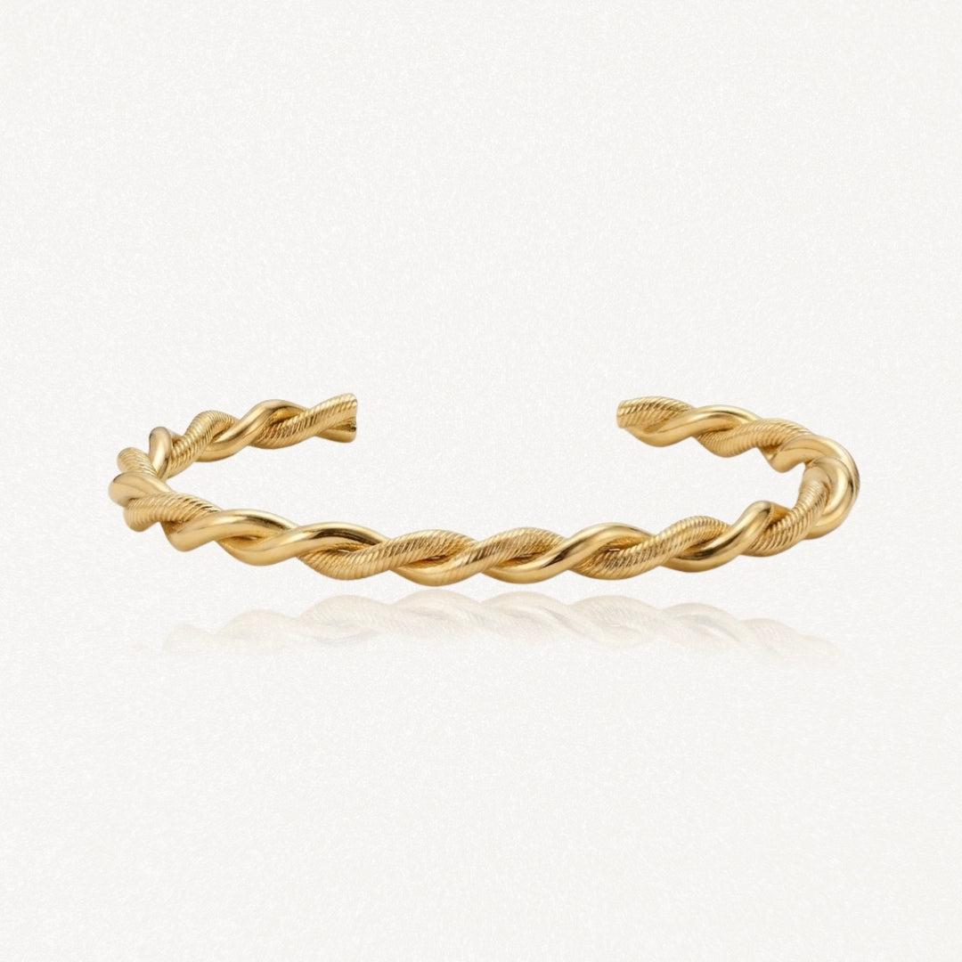 Bracelet manchette torsadé doré, une bande lisse et une bande texturée s'entrelacent.