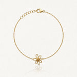 Bracelet fin en acier inoxydable doré, pendentif fleur ajourée cœur granuleux, fermoir mousqueton et chaînette de réglage.
