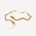 Bracelet doré en forme de serpent ondulé avec deux têtes de serpent se faisant face, chacune ornée d'un petit brillant.