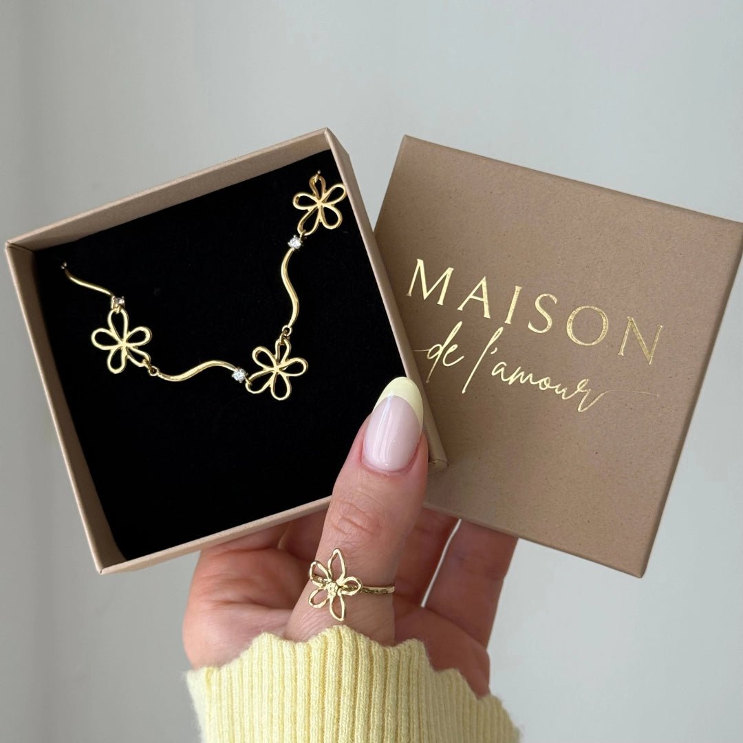 Bracelet en acier inoxydable doré, 3 fleurs ajourées et 2 strass, présenté dans une boîte cadeau.