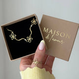 Bracelet en acier inoxydable doré, 3 fleurs ajourées et 2 strass, présenté dans une boîte cadeau.