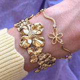 Bracelet en acier inoxydable doré: un épais floral, grandes fleurs texturées, et un fin avec fleur ajourée et brillant.