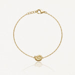 Bracelet doré à chaîne fine avec fermoir mousqueton et breloque coquillage spiralé au centre.
