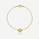 Bracelet doré à chaîne fine avec fermoir mousqueton et breloque coquillage spiralé au centre.