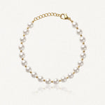 Bracelet de perles blanches rondes alternant avec des petites perles en acier inoxydable doré, fermoir mousqueton.