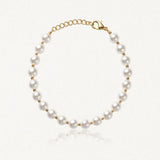 Bracelet de perles blanches rondes alternant avec des petites perles en acier inoxydable doré, fermoir mousqueton.