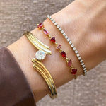 Trois bracelets en acier inoxydable doré portés au poignet, dont un jonc, une chaîne à strass et une chaîne à motifs