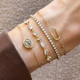 Quatre bracelets en acier inoxydable doré, ornés de strass en zirconium, portés ensemble sur un poignet