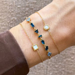 Trois bracelets en acier inoxydable doré avec des strass en zirconium bleus et des détails nacrés sur un poignet