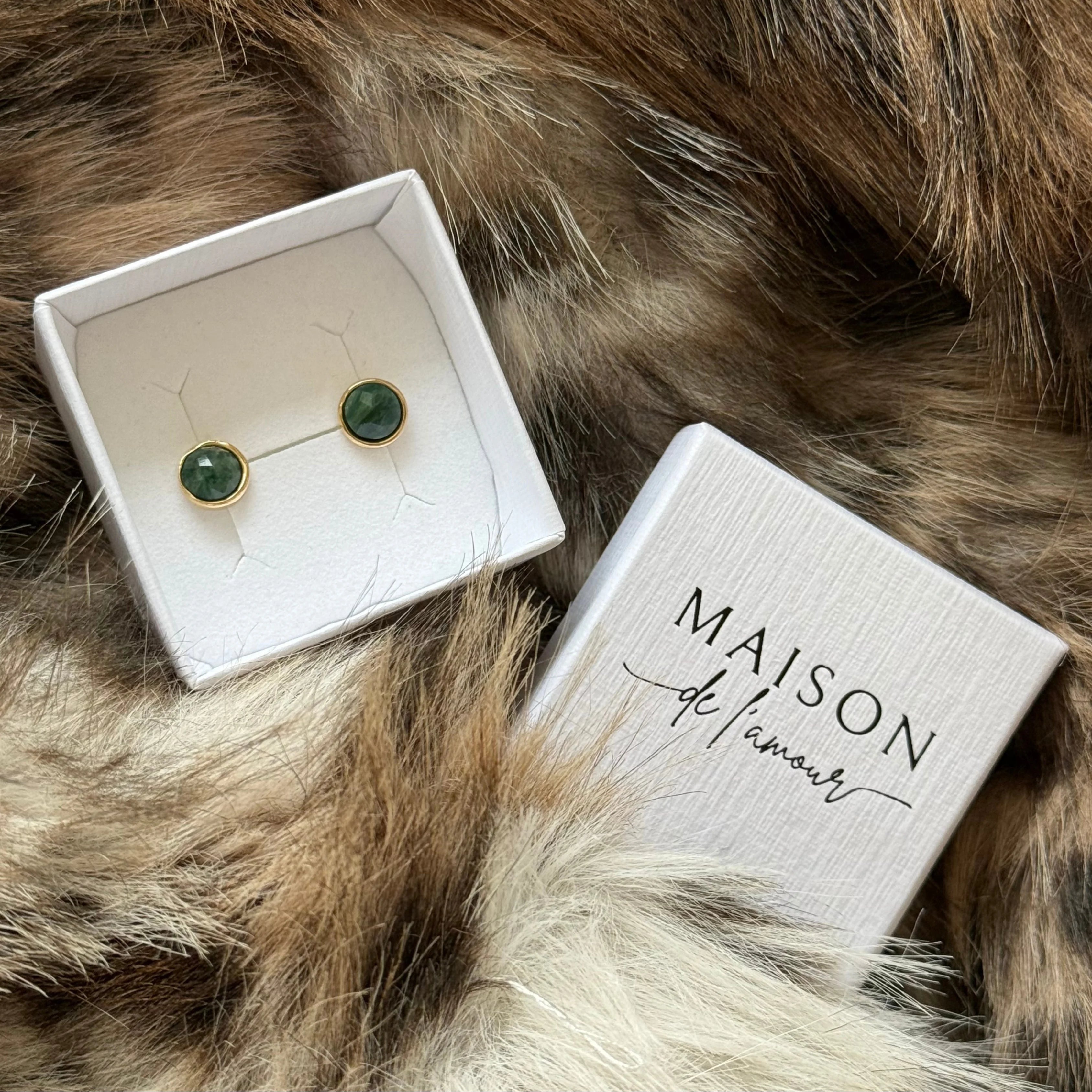 Puces d'oreilles vertes présentées dans leur écrin cadeau blanc signé MAISON DE L'AMOUR, parfait pour offrir.