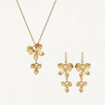 Collier et boucles d'oreilles en acier inoxydable doré. Le pendentif et les boucles se composent de fleurs stylisées