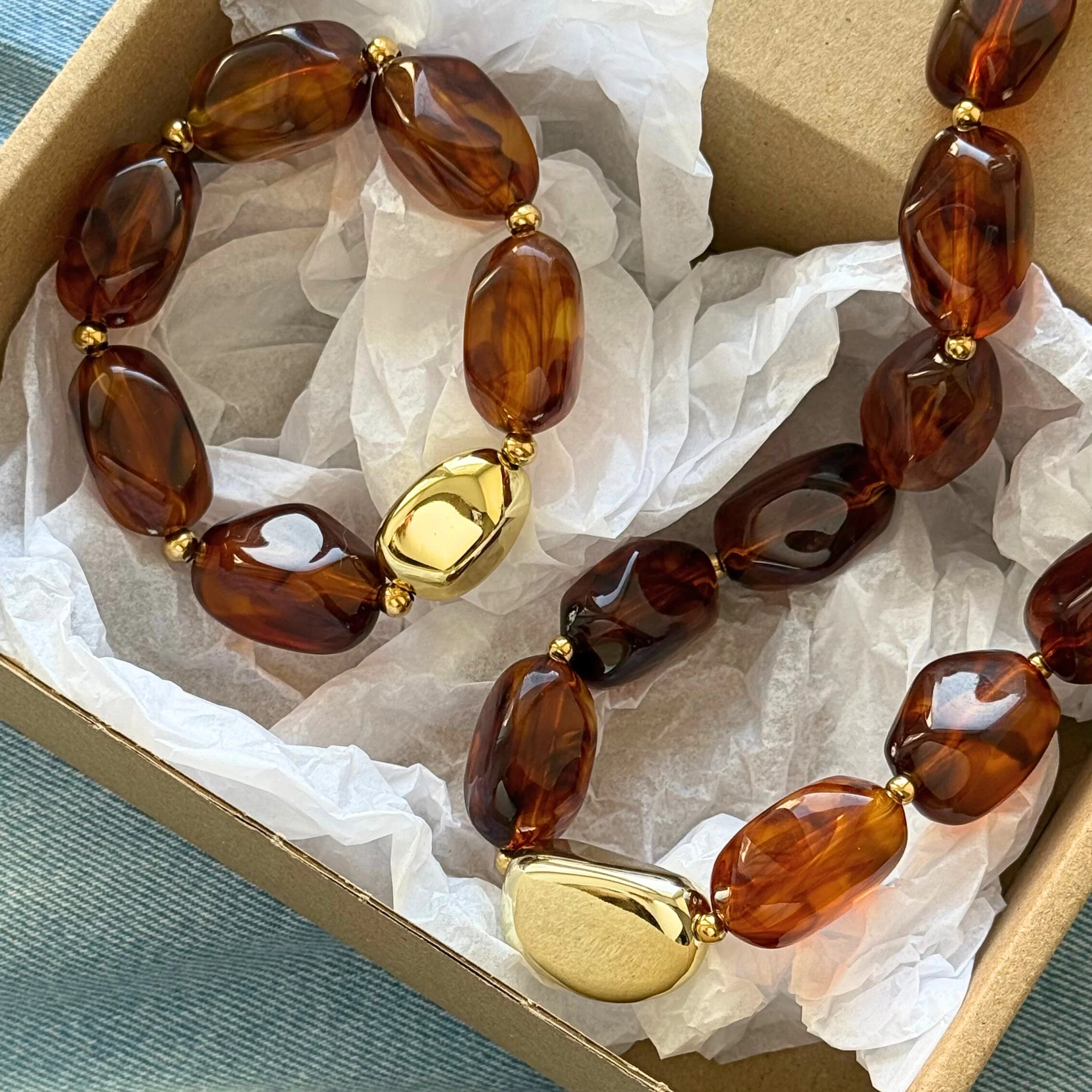 Bijoux soigneusement emballés dans une boîte carton avec papier de soie blanc, prêts pour la livraison.