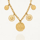 Collier à maillons épais couleur or, orné de cinq pendentifs. Un grand médaillon central avec une rose des vents, deux charms soleils souriants et deux pièces antiques.