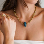 Collier maille épaisse en acier inoxydable doré, avec pendentif pierre bleue en acétate facetté.