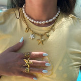 Collier double: un rang de perles, un rang chaîne en acier inoxydable doré avec charms étoiles de mer et coquillages.
