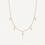 Collier délicat en acier inoxydable doré, chaîne fine avec 5 petites perles blanches pendantes sur fond clair.