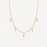 Collier délicat en acier inoxydable doré, chaîne fine avec 5 petites perles blanches pendantes sur fond clair.