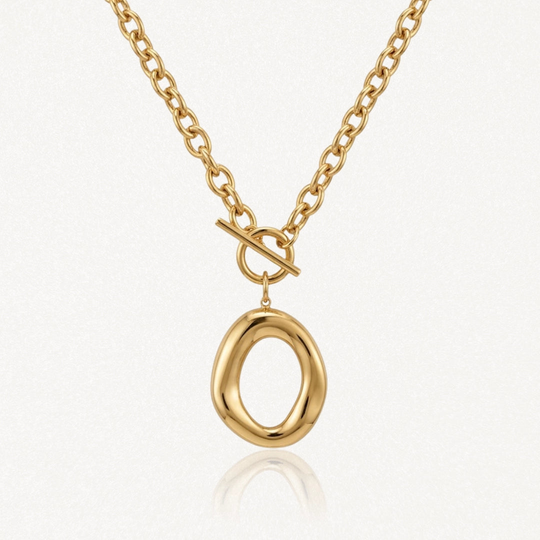 Collier en acier inoxydable doré, chaîne à gros maillons, fermoir toggle et pendentif ovale irrégulier brillant.