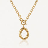 Collier en acier inoxydable doré, chaîne à gros maillons, fermoir toggle et pendentif ovale irrégulier brillant.
