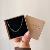 Collier Blair en acier inoxydable doré avec des strass en zirconium bleus dans une boîte cadeau Maison de l'Amour