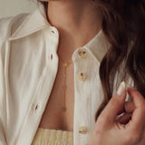 Collier en acier inoxydable doré, chaîne longue avec trois pendentifs fleurs, porté par une femme.