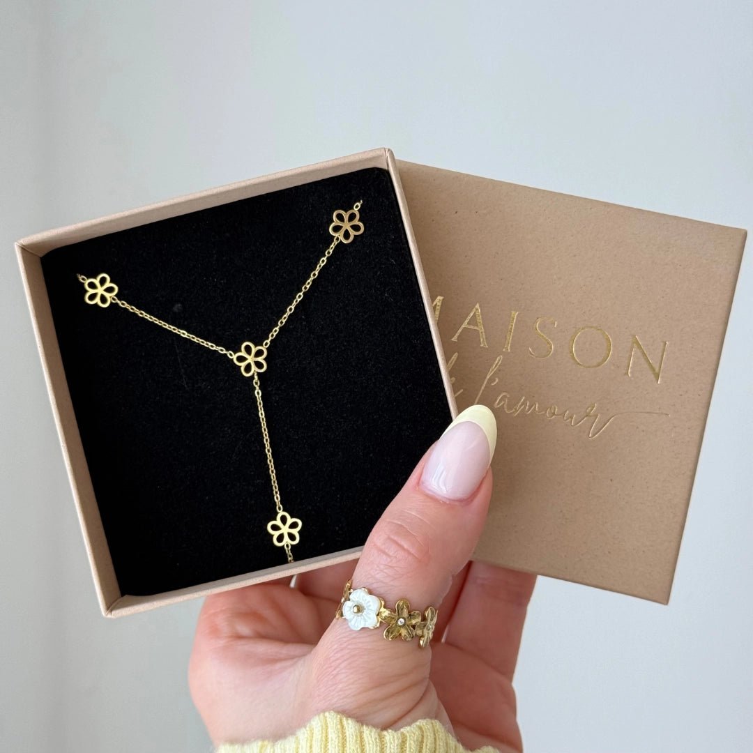Collier en acier inoxydable doré à motifs fleurs style lariat, dans une boîte cadeau Maison Lamour.