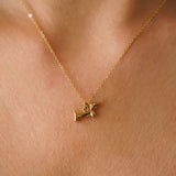 Collier avec pendentif teckel en acier inoxydable doré, porté autour du cou.