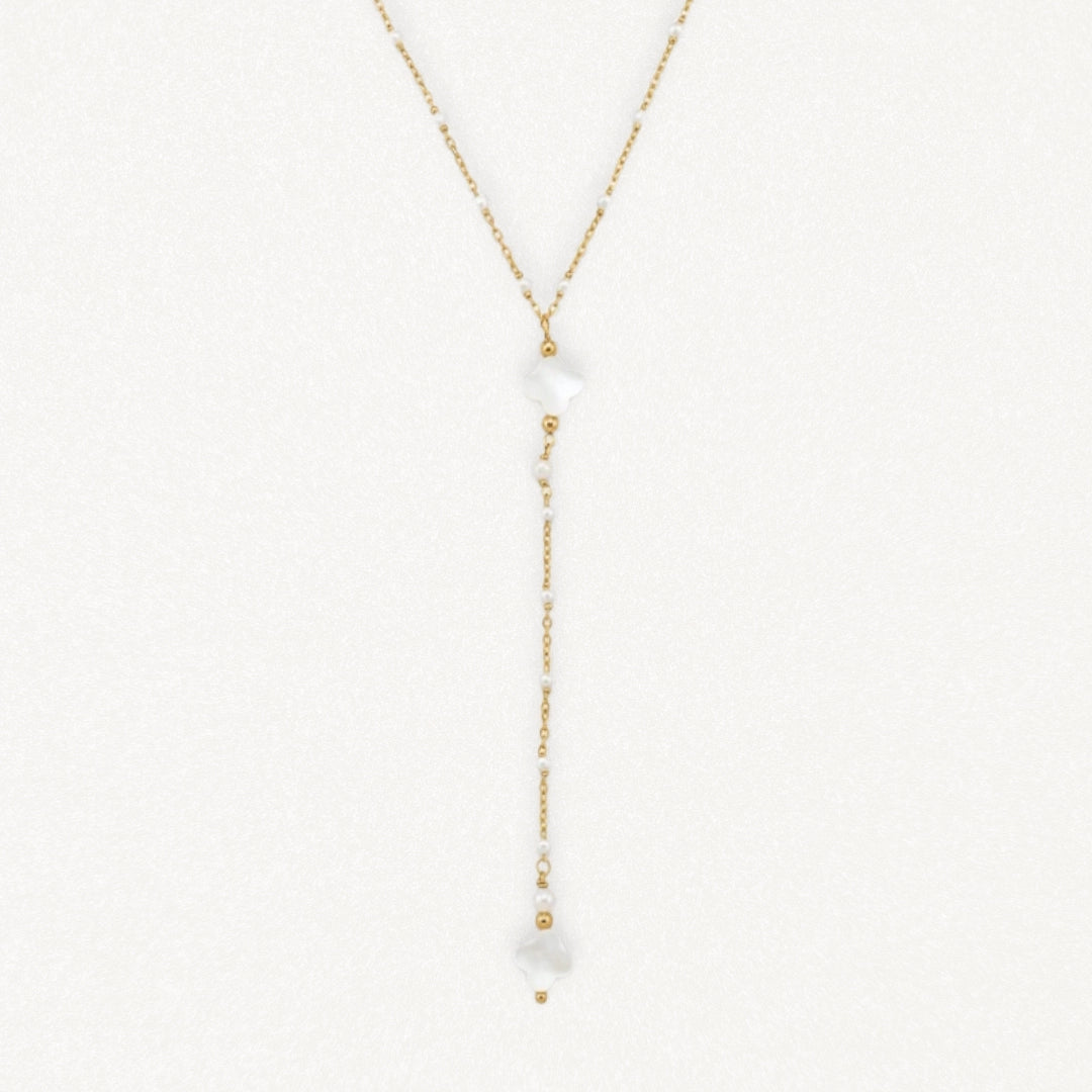 Collier lariat en acier inoxydable doré avec perles blanches, petits trèfles en nacre et billes dorées.