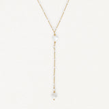 Collier lariat en acier inoxydable doré avec perles blanches, petits trèfles en nacre et billes dorées.