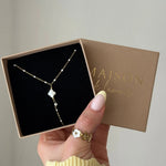 Collier acier inoxydable doré, petites perles blanches, pendentif trèfle blanc nacre, dans sa boîte "Maison de l'amour".