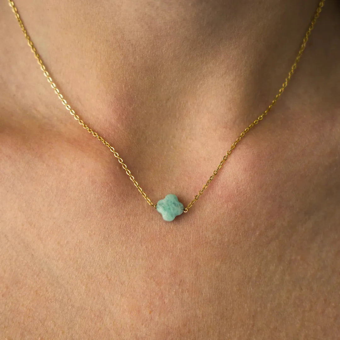 Collier fin en acier inoxydable doré avec pendentif trèfle en Amazonite sur le cou d'une personne.