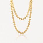 Collier long en acier inoxydable doré, composé de disques ronds martelés, élégamment drapé en deux rangs.